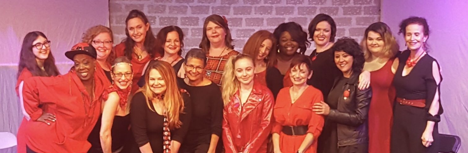 Melanie with a cast of women dressed in red and black after a performance
